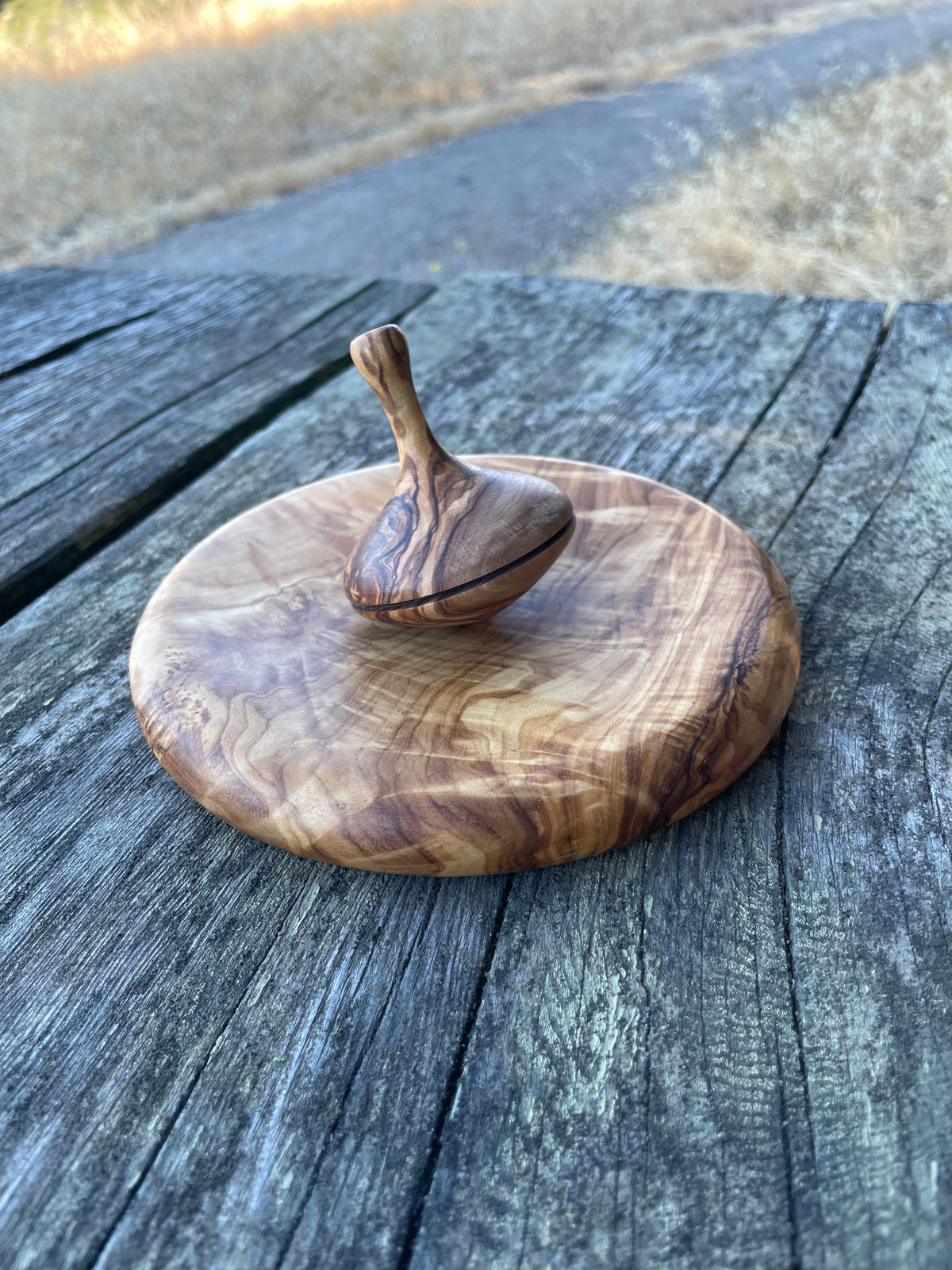 Handmade olive wood spinning top toy with natural grain
