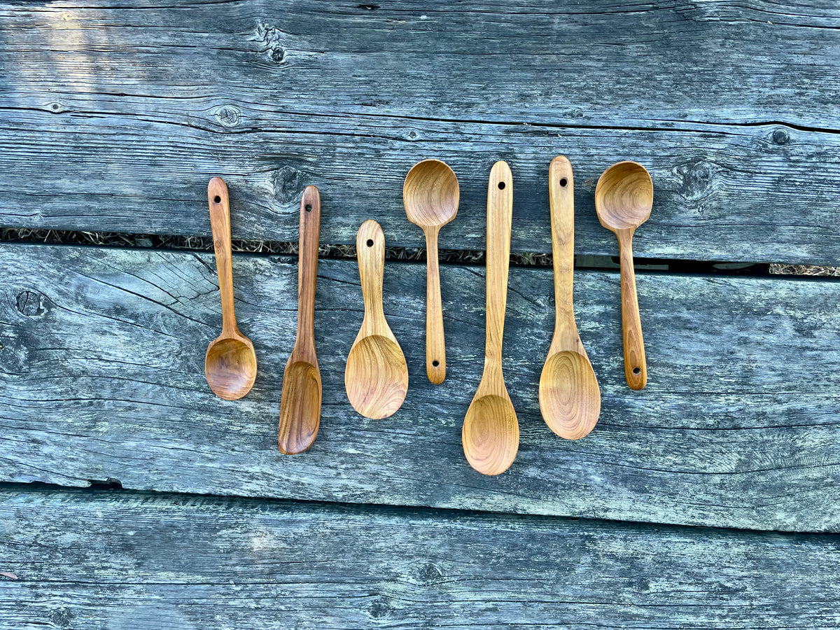 Seven-piece teak wood spoon set on weathered wood