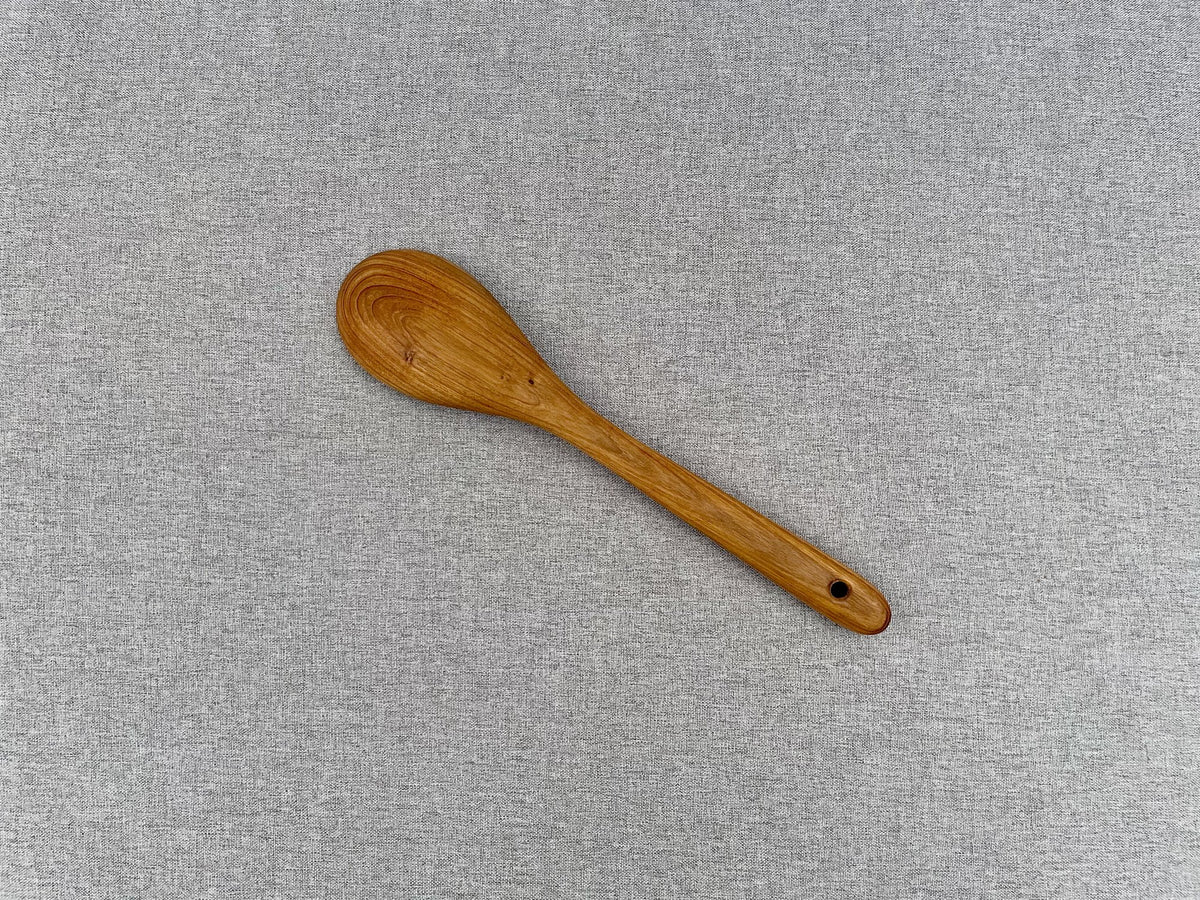 Teak wood cooking spoon with rounded bowl, angled view
